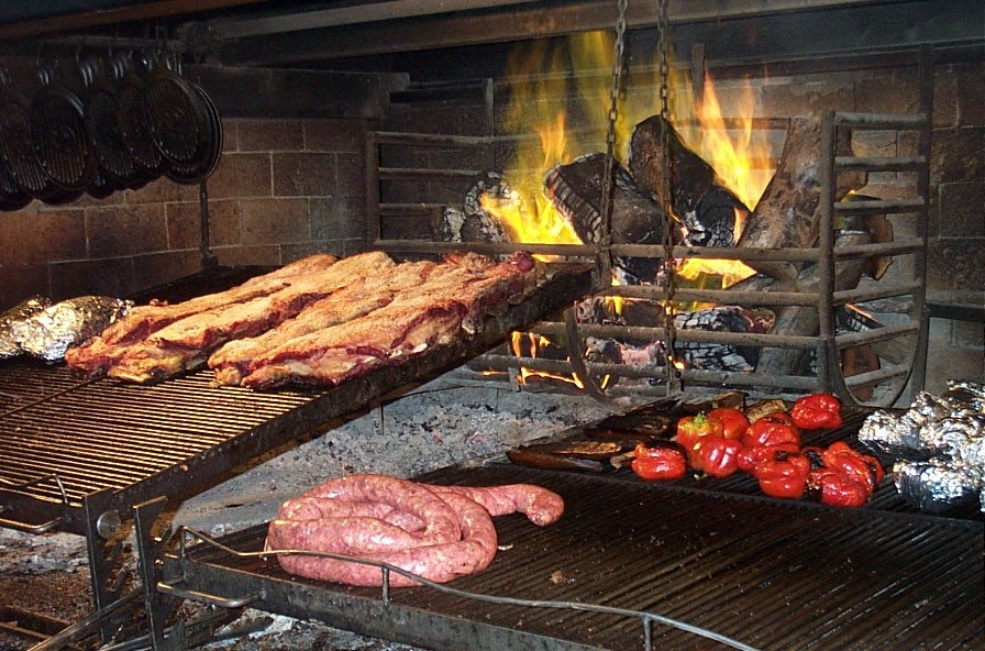 Ribs and sausage on an Argentine parrilla beside a wood fire