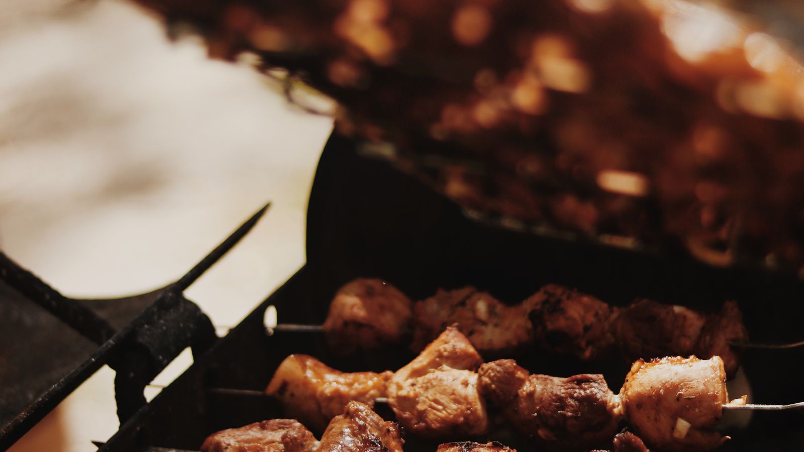 Skewers of marinated meat grilling over coals with flatbread