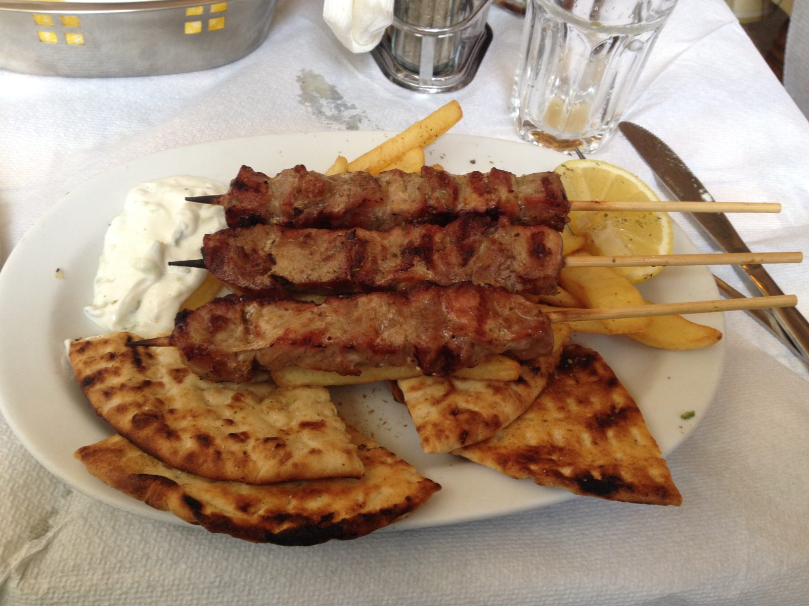 Grilled pork souvlaki with pita, tzatziki and fries