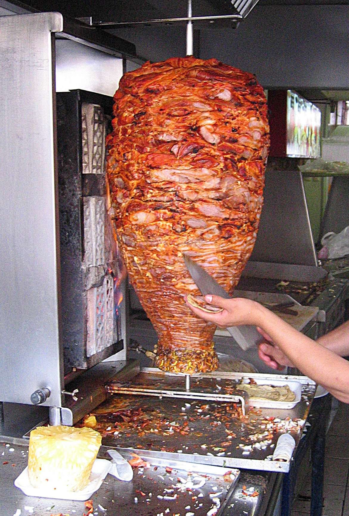 Vertical trompo of al pastor pork topped with pineapple