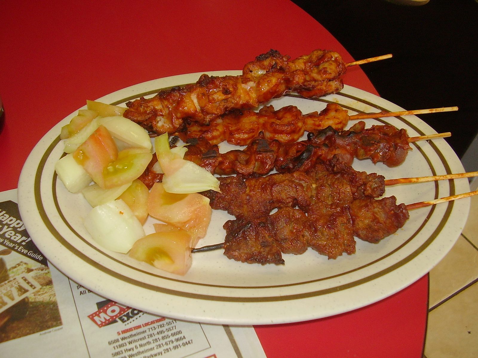 Plate of spiced grilled meat skewers with onion and tomato
